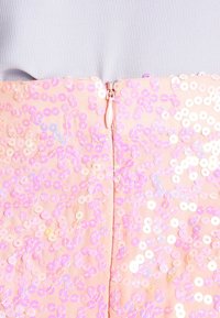 Tessuto di abito decorato con paillettes in morbido rosa, con una superficie lucida e un dettaglio di zip centrale. Accenti riflettenti di luce in tutto l'abito.