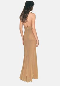 Back view of a long, form-fitting, strapless dress in a nude color, made from sheer fabric with a zipper closure at the back.