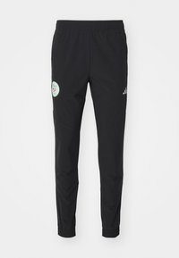 Zwarte sportbroek met een elastische tailleband, ritszakken, taps toelopende pijpen en een cirkelvormige logopatch op de linkerdij.