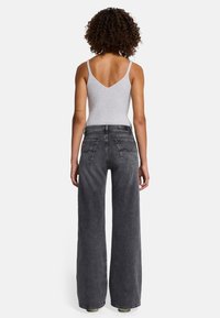 Jean large taille haute gris avec une texture légèrement délavée, associé à un haut débardeur ajusté gris clair à côtes, doté de fines bretelles.