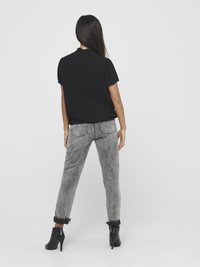 Black short-sleeve top with a textured pattern, paired with faded grey jeans and black heeled ankle boots. Simple, casual outfit design.