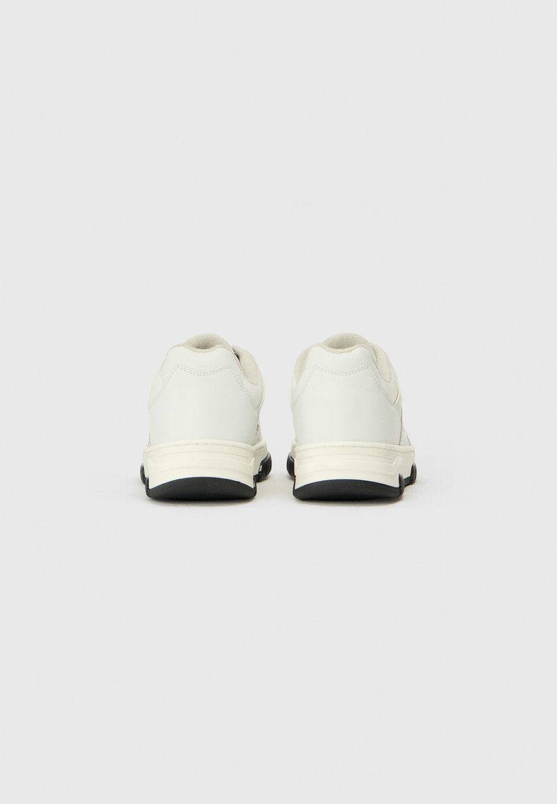 Weiße Sportschuhe mit glattem Lederoberteil, gepolstertem Kragen und schwarzer Gummisohle. Minimalistisches Design ohne auffällige Muster oder Akzente.