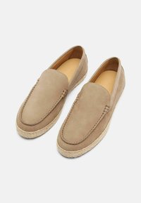 Beige nubuck slip-on sko med rund t�å og syede detaljer, der har en jute reb sål for ekstra tekstur og kontrast.