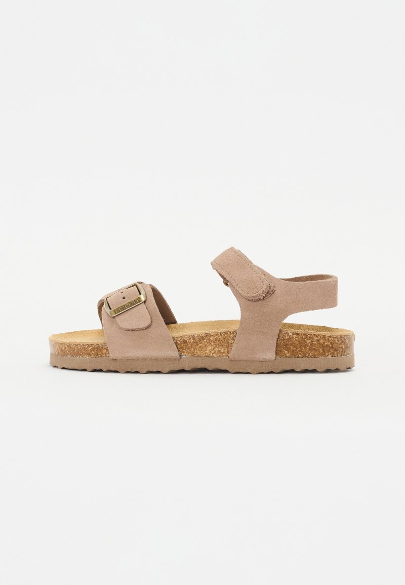 Brun mockasin sandal med justerbar spänne, korkfotbädd och texturerad gummisula. Öppen bakdesign med minimalistisk stil.