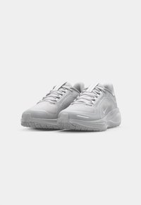 White athletic shoes featuring a textured mesh upper, padded collar, and rubber outsole with traction patterns; minimalistic logo detail.