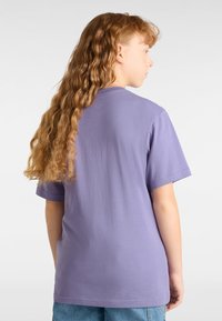 Camiseta de algodón morada con mangas cortas, cuello redondo y corte relajado, mostrando la vista trasera. Textura suave y diseño sencillo.