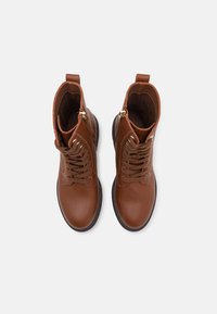 Brune lær ankle boots med teksturert overflate, rund tå, snøring foran og glidelåsdetalj på siden. Gummisåle.