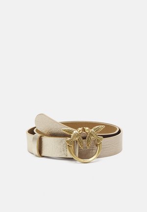 Opgerolde metalen gouden leren riem met een ronde gouden gesp met twee tegenover elkaar kijkende vogels met gegraveerde vleugeldetails.