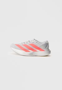 Chaussure de sport grise avec des rayures roses vives, partie supérieure en mesh léger, accents réfléchissants et semelle texturée pour une meilleure adhérence.