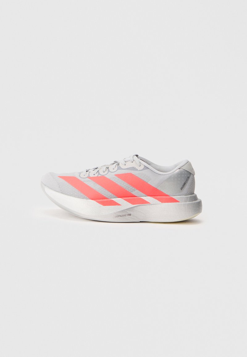Chaussure de sport grise avec des rayures roses vives, partie supérieure en mesh léger, accents réfléchissants et semelle texturée pour une meilleure adhérence.