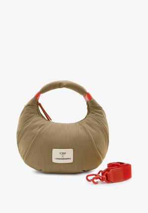 Beige ribbed fabric handbag with rounded handle, red zipper pull, logo patch, and detachable wide red strap with clips beside it.