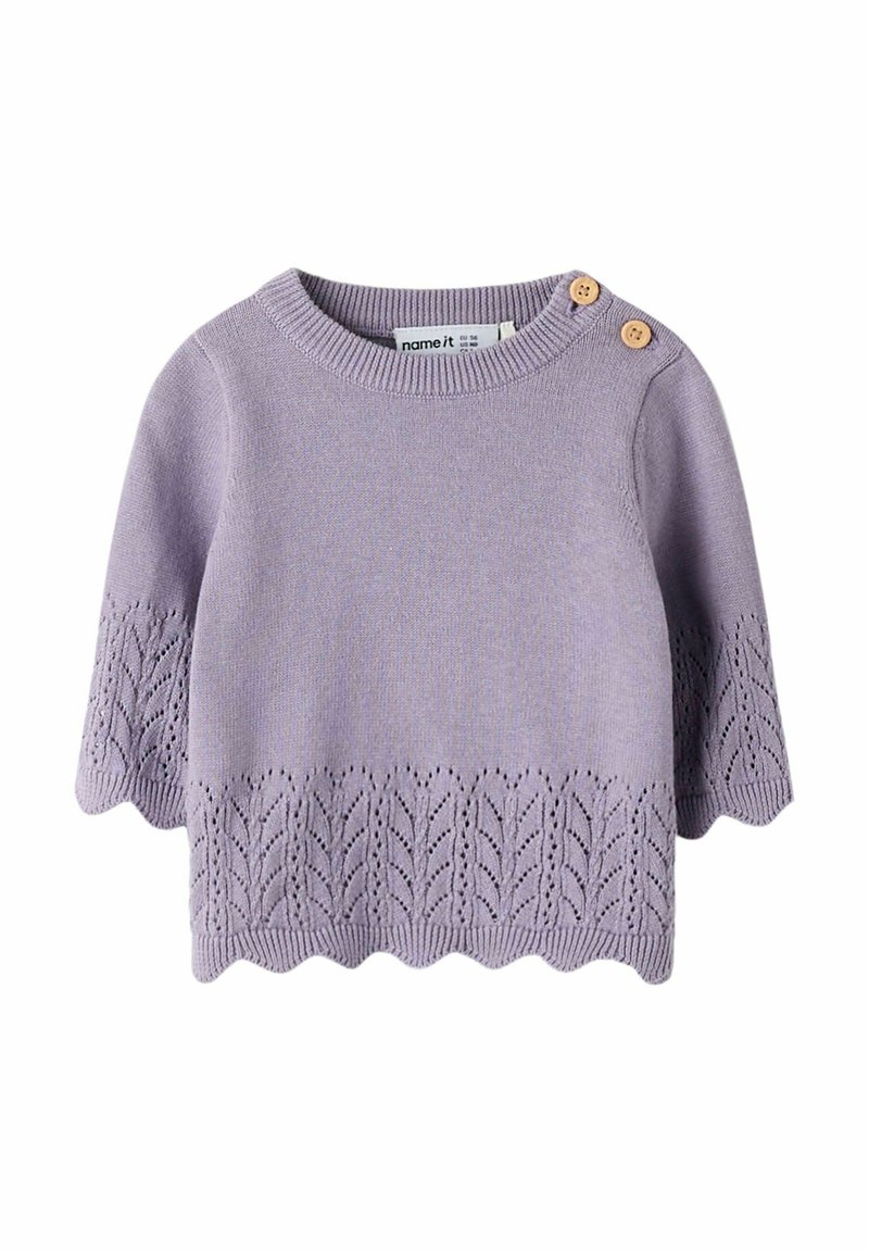 Pull en tricot lilas à manches courtes, avec un ourlet festonné et un motif de feuilles en bas. Deux boutons beiges à l'épaule.