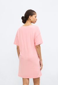Ροζ φόρεμα με κοντά μανίκια από απαλό ύφασμα, με άνετη εφαρμογή και στρογγυλή λαιμόκοψη, με ελαφρώς κυρτή γραμμή στο κάτω μέρος.