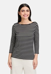 Czarny i biały pasiasty top z długim rękawem, z dekoltem łódkowym, wykonany z miękkiego materiału. Posiada rękawy do trzech czwartych oraz luźny krój.