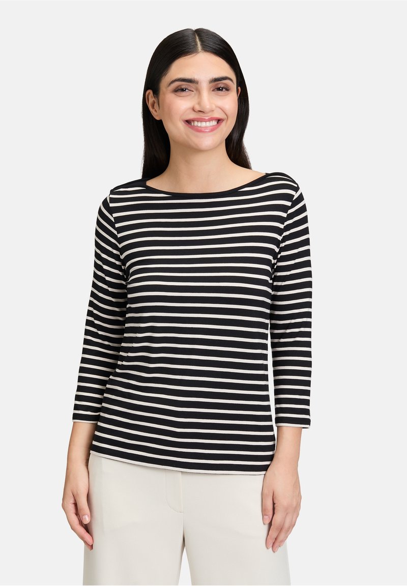 Czarny i biały pasiasty top z długim rękawem, z dekoltem łódkowym, wykonany z miękkiego materiału. Posiada rękawy do trzech czwartych oraz luźny krój.