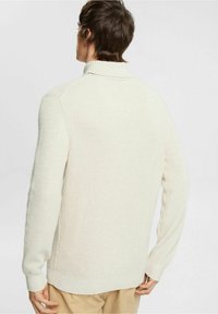 Hellbeiger Strickpullover mit hohem Kragen und Rippstruktur, ausgestattet mit langen Ärmeln und Seitenschlitzen für eine lässige Passform.