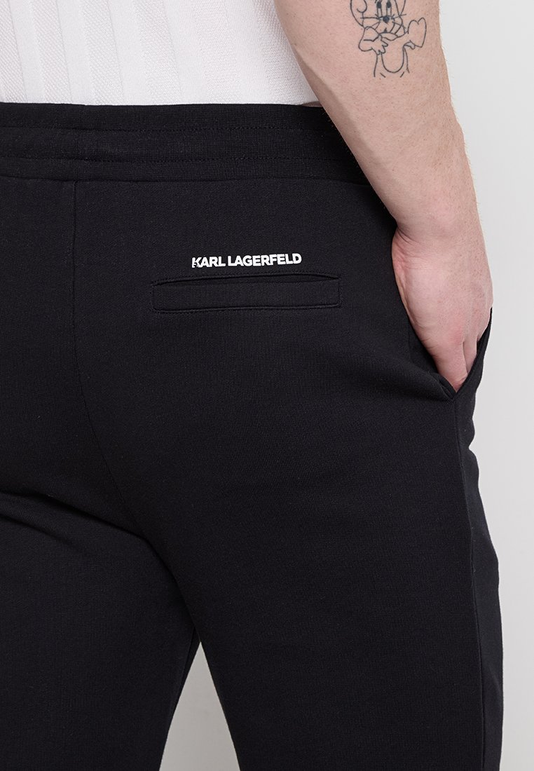 Pantaloni neri con vita elastica, dotati di una tasca sul retro con il logo bianco "KARL LAGERFELD". Tessuto liscio, design semplice e vestibilità sartoriale.
