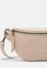 Bolso cruzado de cuero durazno con forma redondeada, cremallera superior, herrajes en tono plateado y una correa desmontable. Presenta un sutil logo en relieve.