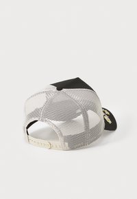 Svart och vit mesh-back keps med en solid svart front, vilket har sömnadsdetaljer på framsidan och en justerbar plastrem i ryggen.