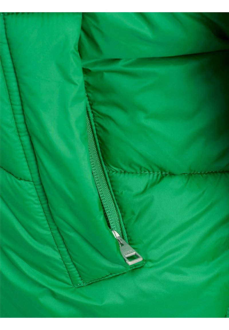 Primo piano di una giacca con imbottitura verde con una cerniera verde parzialmente aperta e pieghe di tessuto circostanti.