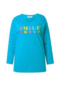 Türkisfarbenes Langarm-T-Shirt aus Baumwolle, mit dem Wort "SMILE" in fetten, bunten Buchstaben über verschiedenen Smiley-Gesichtern.