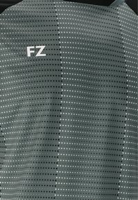 Grön sporttröja med ett prickigt mönster i svart och vitt. Har en "FZ"-logga i vitt på övre vänstra sidan. Mjuk material, atletisk passform.