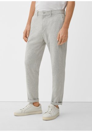Hellgraue Sweatpants aus weichem Stoff, mit geradem Schnitt, vorderen Taschen und einem umgeschlagenen Saum. Kombiniert mit weißen Turnschuhen.
