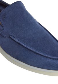 Marinblå mocka slip-on sko med en slät yta, vit gummi sula och minimala sömnadsdetaljer längs kanten.