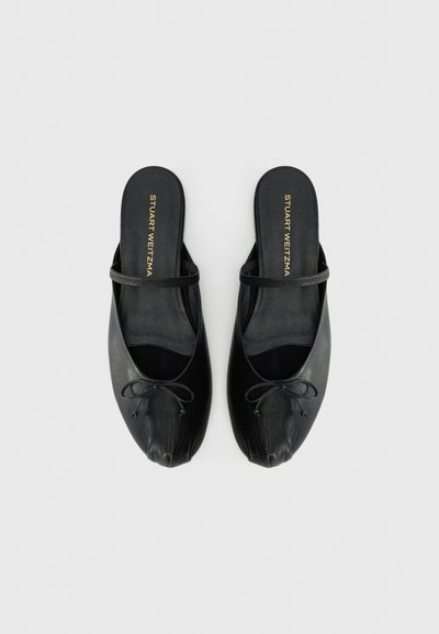 Black leather slip-on flats with a small bow and thin strap, labeled "Stuart Weitzman" on the insole, shown from above.