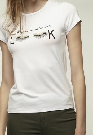 Weißes eng anliegendes T-Shirt mit schwarzen Buchstaben "L" und "K" und zwei 3D falschen Wimpern mit Perlen darüber, getragen von einer Person mit heller Haut.