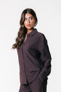 Camicetta button-up di un violaceo scuro con un motivo geometrico testurizzato, maniche lunghe e colletto a punta, con una vestibilità rilassata e tasca anteriore.