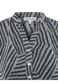 Bluse mit Knöpfen und geometrischem Streifenmuster in Marineblau und beige. Der Stoff ist strukturiert und hat ein weiches, leichtes Tragegefühl.