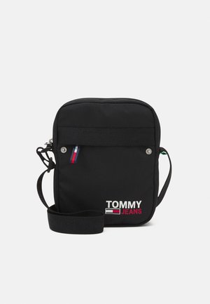 Schwarze Umhängetasche mit Reißverschluss, hergestellt aus strapazierfähigem Stoff. Verfügt über das Tommy Jeans Logo in Weiß und Rot sowie einen verstellbaren Riemen.