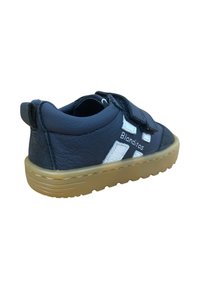 Zapato de cuero azul marino con acentos blancos, correas de Velcro y suela de goma. Presenta un cuello acolchado y superficie texturizada.