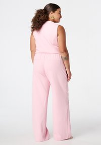 Roze jumpsuit met wijd uitlopende benen, mouwloos ontwerp, elastische tailleband en achterzakken. Soepele, lichtgewicht stof, minimalistische stijl.