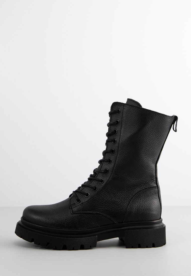Czarne skórzane buty bojowe z okrągłym noskiem, wyściełanym kostką, sznurowanym przodem i zamkiem bocznym. Gruba, teksturowana podeszwa zapewniająca przyczepność.