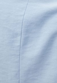 Světle modrá tkanina s hladkým povrchem. Vyznačuje se diagonálním vzorem tkaní s jemným leskem a precizním šitím podél švů.