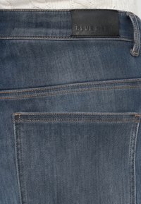 Tmavomodré džínsy s textúrovaným povrchom, detailom na zadnej ...