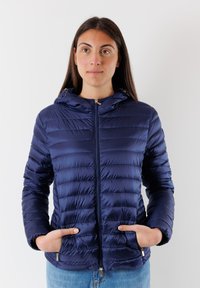 Giacca puffer blu navy con cappuccio, caratterizzata da un design trapuntato, chiusura con zip e tasche laterali. Testura liscia e lucida con dettagli in metallo.