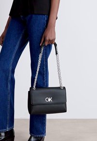 Black leather handbag with a silver chain strap and logo, featuring a sleek rectangular shape and smooth texture.