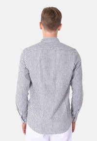 Camicia a maniche lunghe in tessuto a righe grigie e bianche, con colletto classico e polsini con bottoni, orlo curvo e spallina sul retro.
