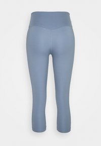 Leggings bleu clair taille haute et coupés, montrés de dos sur un fond blanc uni.