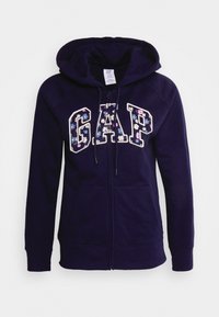 Felpa navy con zip, con lettering floreale "GAP", realizzata in materiale felpato. Presenta un cappuccio e tasche frontali. Texture liscia.