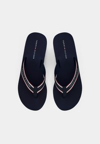 Navy flip-flops with a textured footbed, featuring a multi-colored strap with red, white, and blue accents and brand logo detail.