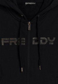 Sudadera negra con cremallera y cordones, tirador de cremallera de metal y la palabra "FREDDY" escrita en pequeños studs metálicos en el pecho.