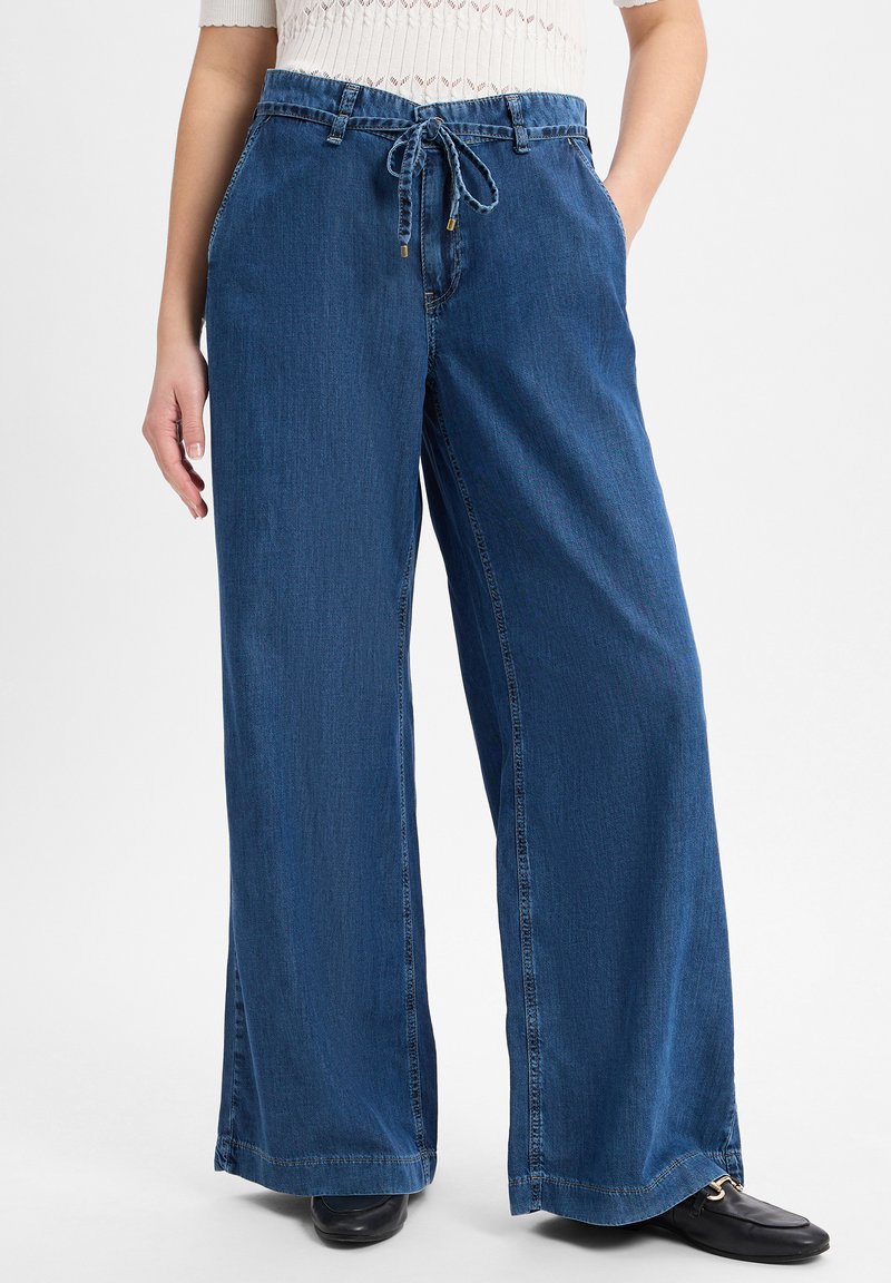 Wide-leg blue denim pants with a drawstring waist, front pockets, and a textured finish. Casual fit with a relaxed silhouette.