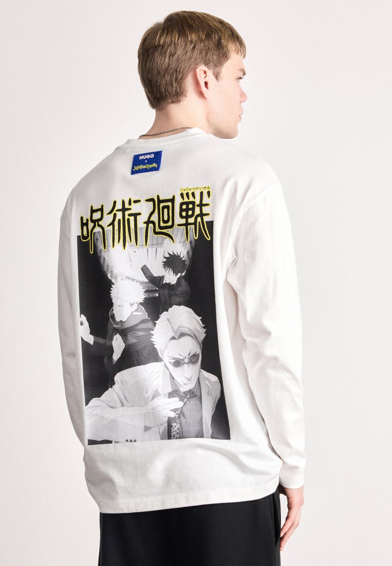 Λευκό μακρυμάνικο μπλουζάκι με σχέδιο ασπρόμαυρης γραφικής εκτύπωσης τριών φιγούρων στην πλάτη, συνοδευόμενο από κίτρινο κείμενο πάνω από την εικόνα.