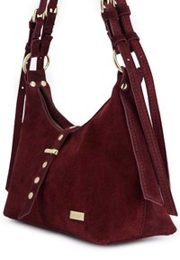 Bordo zamszowa torebka o ustrukturyzowanym designie, z złotymi akcentami metalowymi oraz regulowanymi paskami z zapięciem na zatrzask i ozdobnymi ćwiekami.
