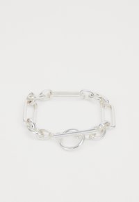 Silver chain bracelet with interlocking oval and rectangular links. Features a toggle closure with a circular accent. Smooth, shiny metal finish.