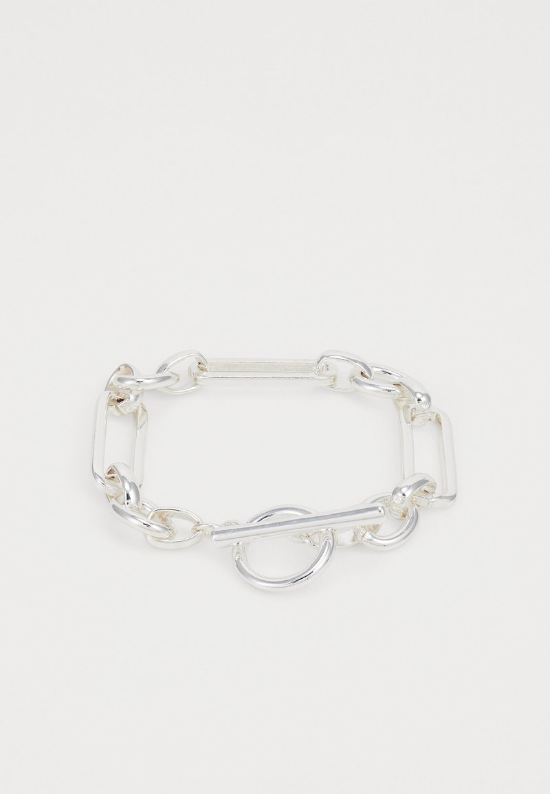 Silver chain bracelet with interlocking oval and rectangular links. Features a toggle closure with a circular accent. Smooth, shiny metal finish.